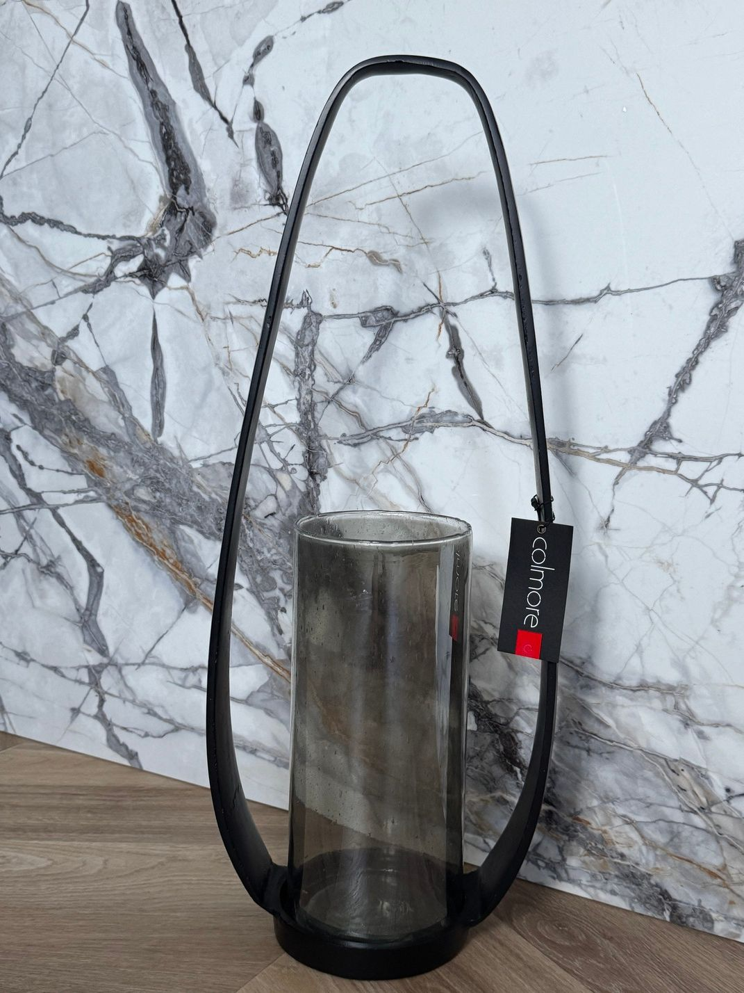 Zwarte metalen lantaarn met een rookkleurige glazen cilinder.