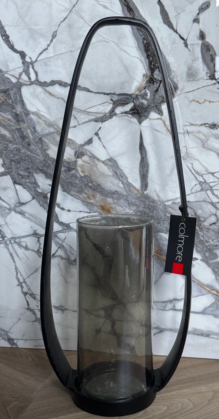 Zwarte metalen lantaarn met een rookkleurige glazen cilinder.