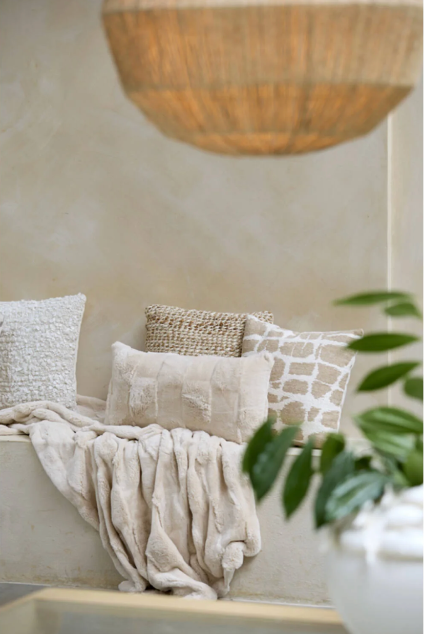 Crèmekleurig, rechthoekig, pluizig kussen met rechthoekige, gestructureerde vlakken.