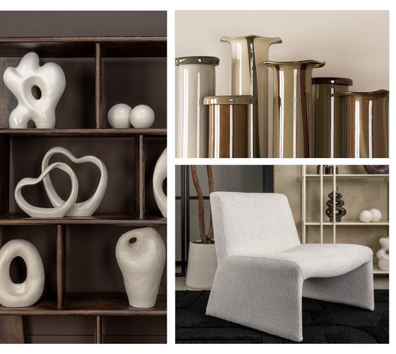 Een wit, hartvormig beeldje op een lichte houten tafel, met abstracte kunst en een plant op de achtergrond.