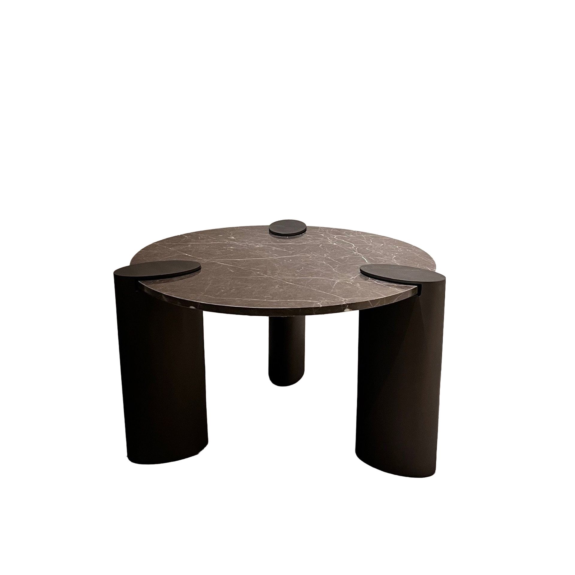 Ronde bruine tafel met drie donkere cilindrische poten op een witte achtergrond.