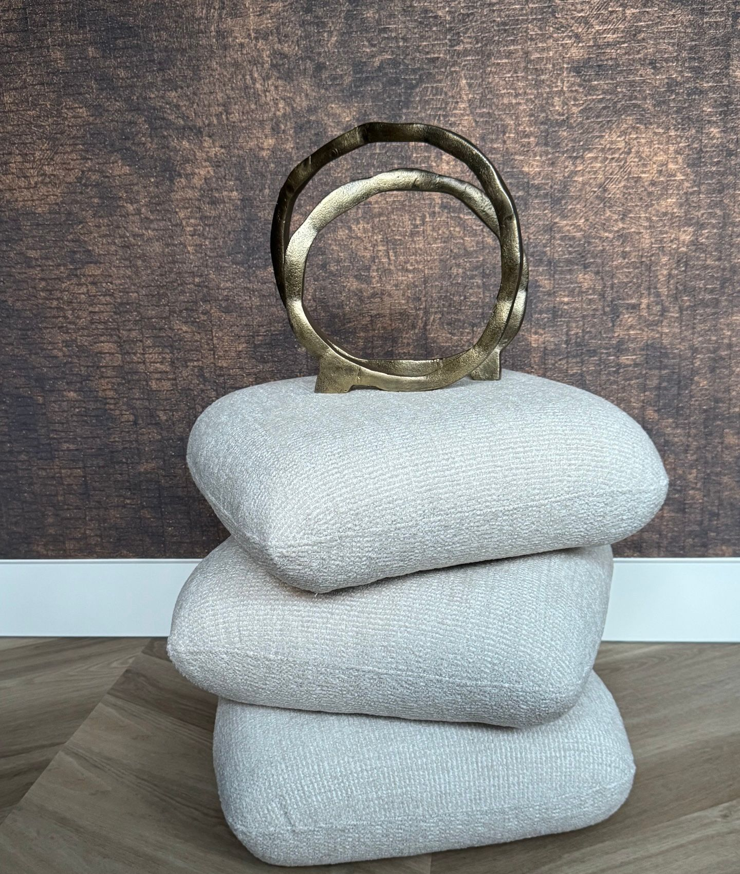 Abstracte gouden metalen sculptuur bestaande uit twee met elkaar verbonden ringen op een donker, rond oppervlak.