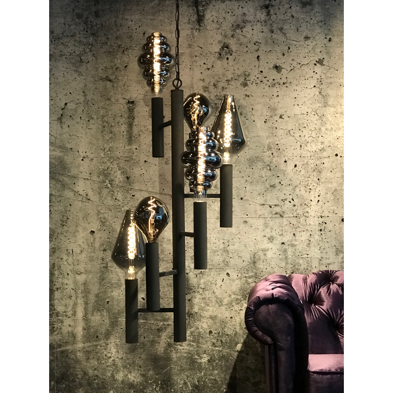Zwarte kroonluchter met vier donkergetinte lampen, tegen een grijze betonnen muur met structuur.