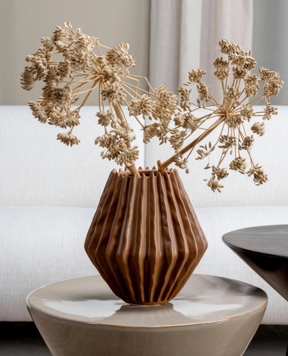 Een verzameling kandelaars van mat glas op een donkere houten tafel, waarvan sommige met brandende kaarsen.