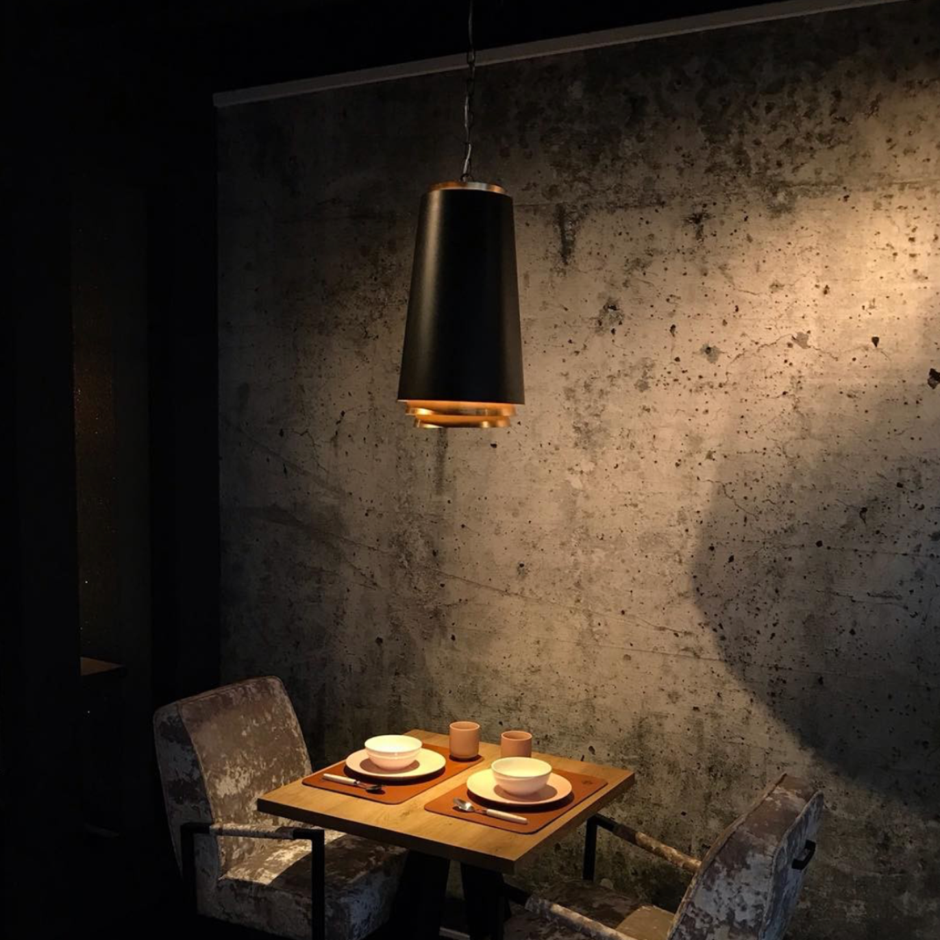 Een zwarte en gouden hanglamp, hangend aan een ketting.