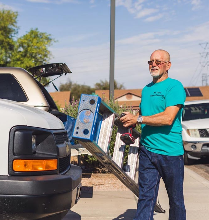 Red and black drill with battery in tool belt on a truck bed.