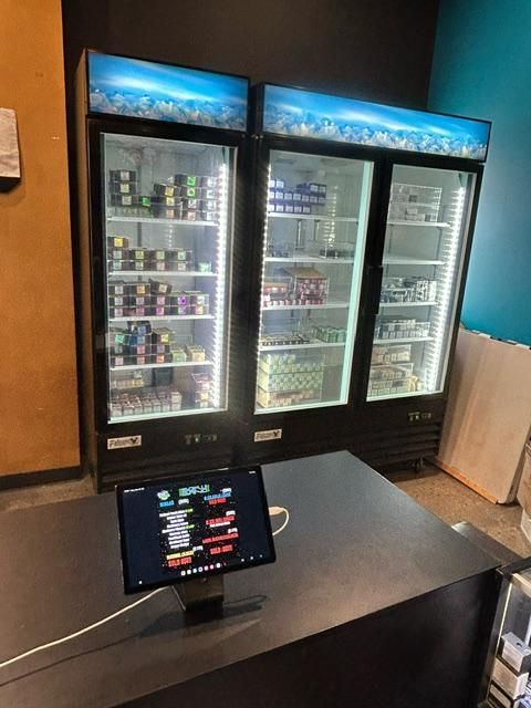 A computer monitor is sitting in front of a refrigerator in a store.
