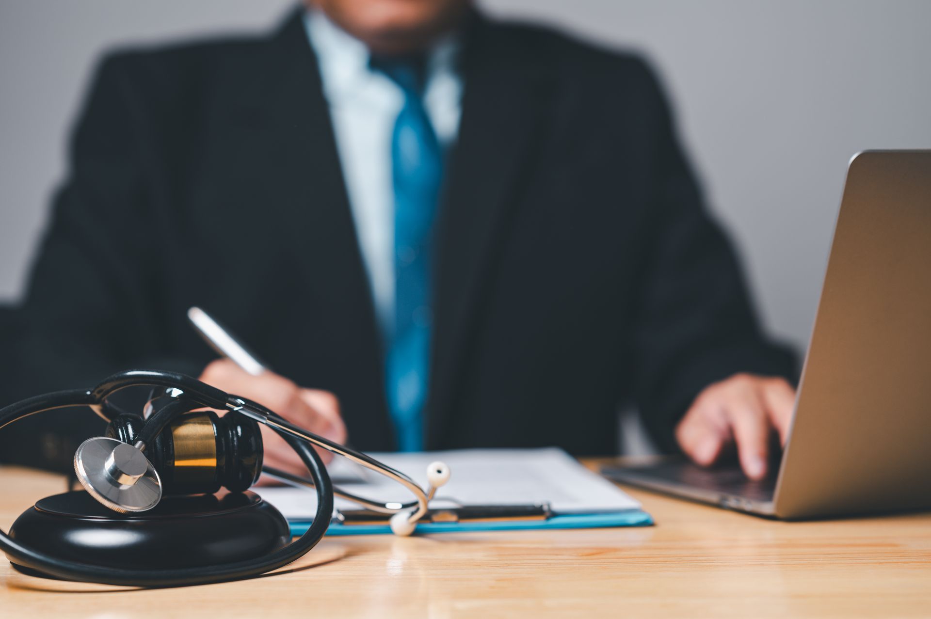 Stethoscope on desk with professional writing and working on laptop.