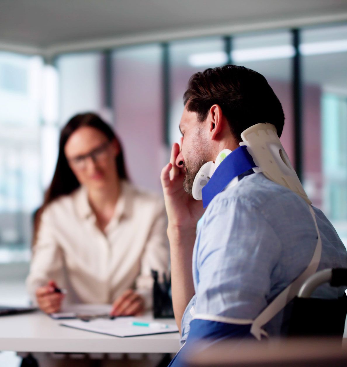 An injured man is talking to a woman in an office.