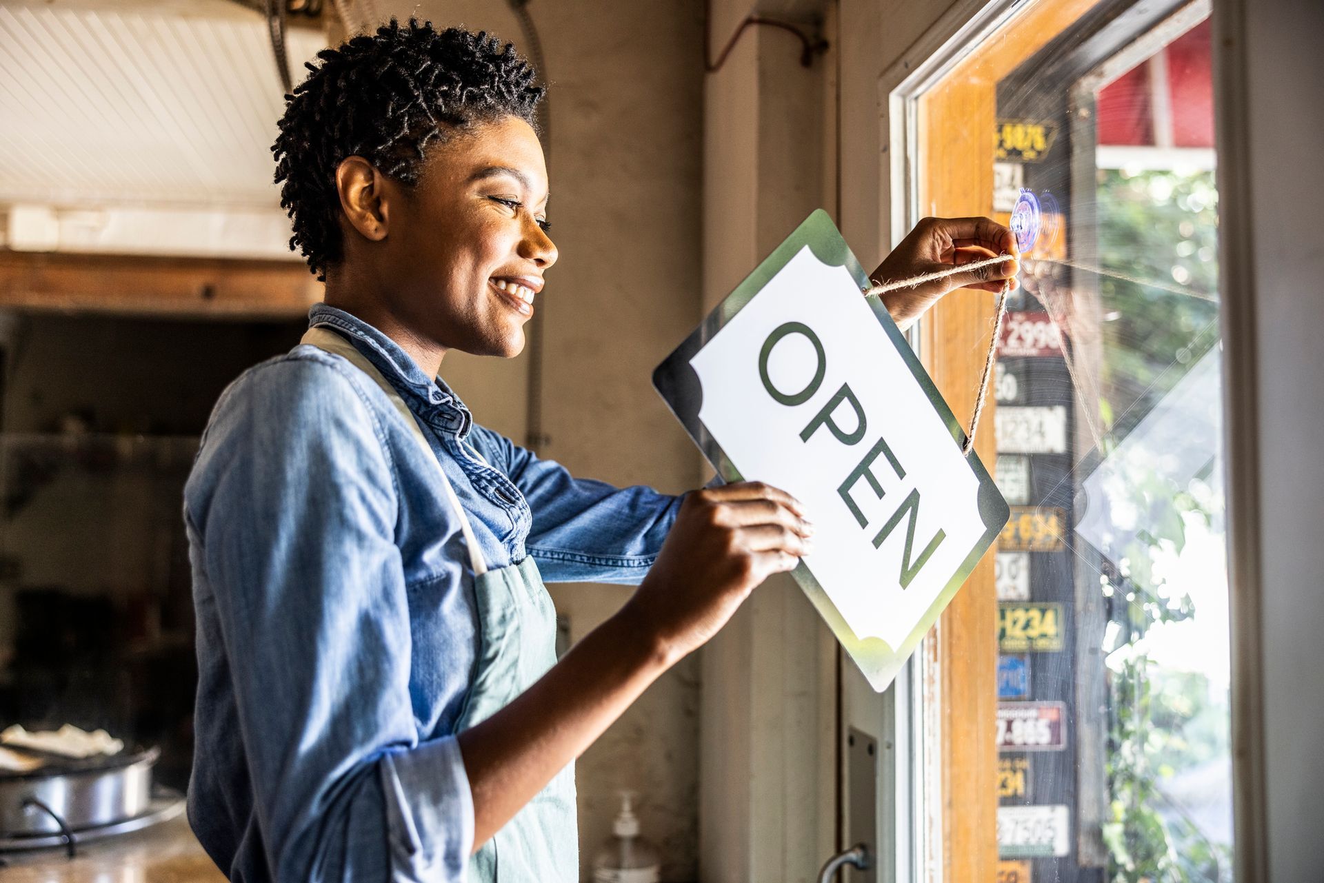 Female small business owner placing open sign in business window | Craven Sign Services