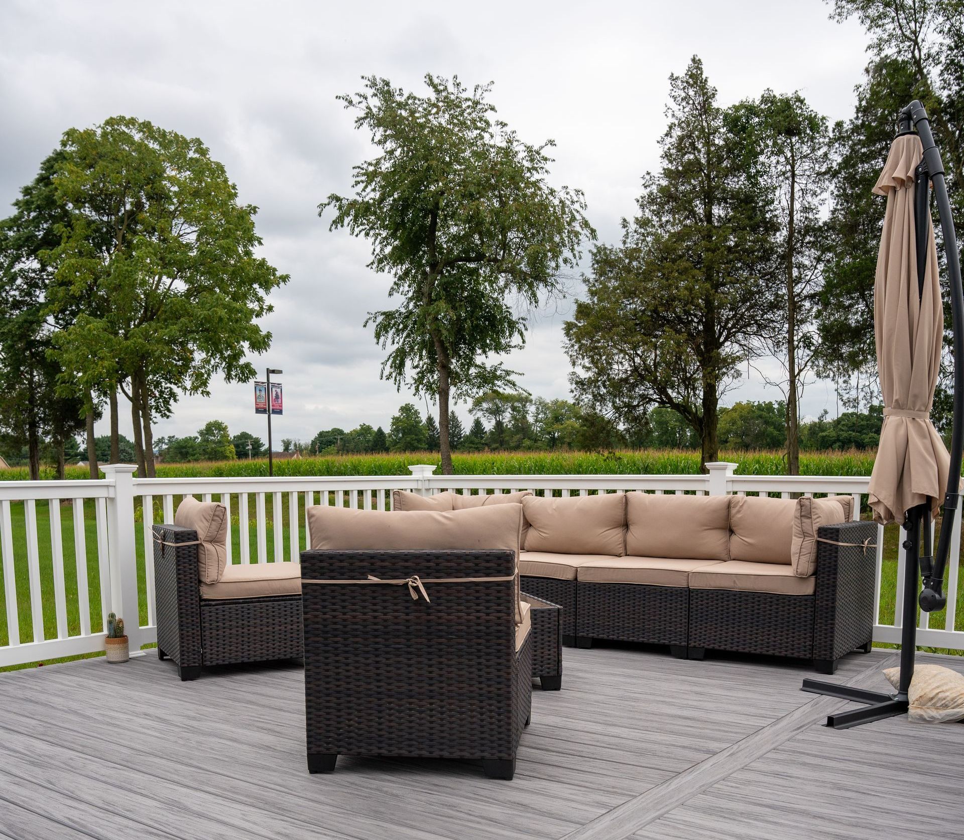 A deck with a couch , chairs , and umbrella on a cloudy day.