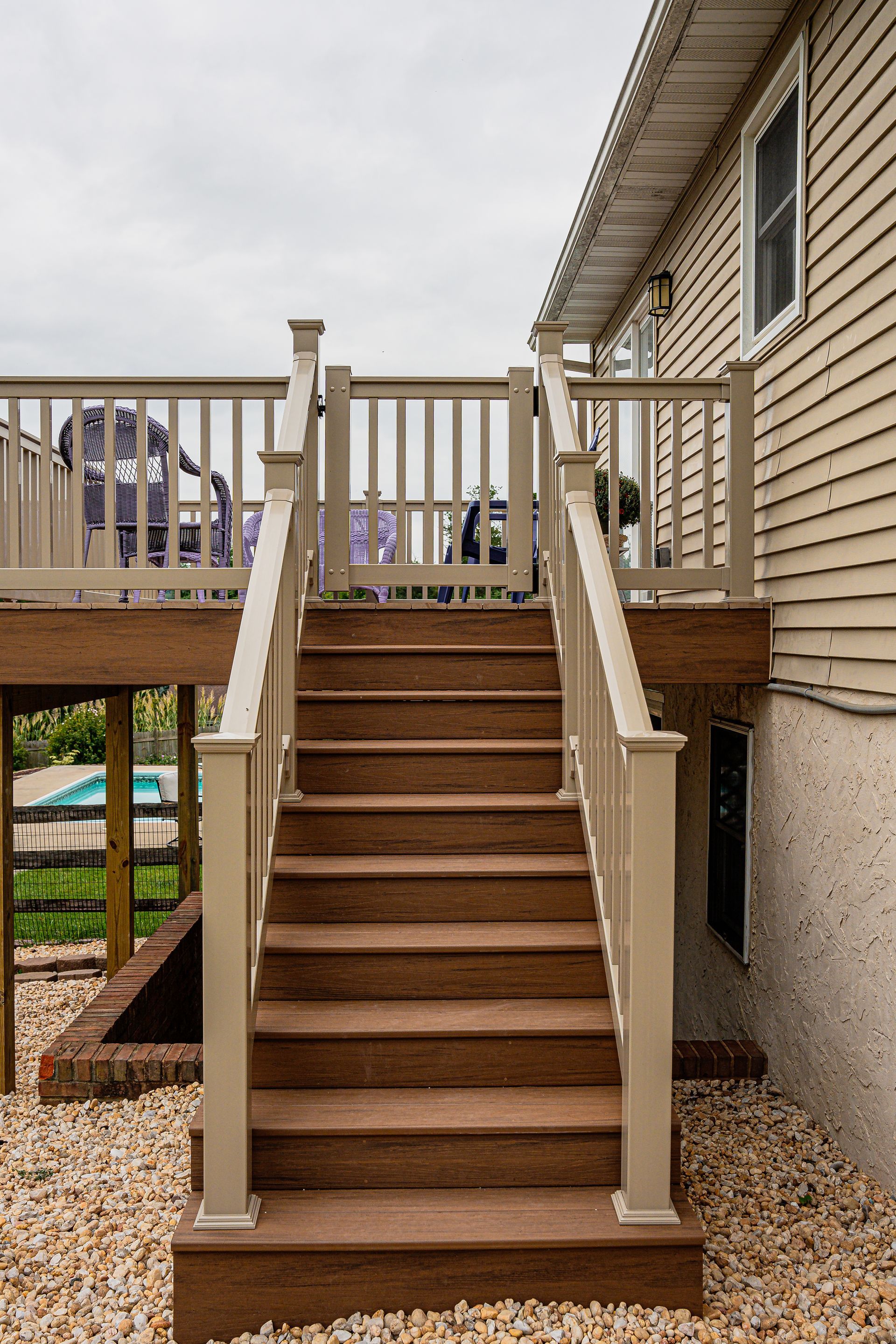 A deck with stairs leading up to it and a house in the background.