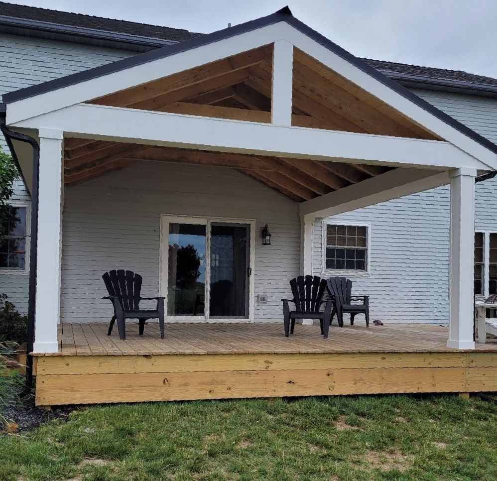 A white house with a wooden deck and chairs on it