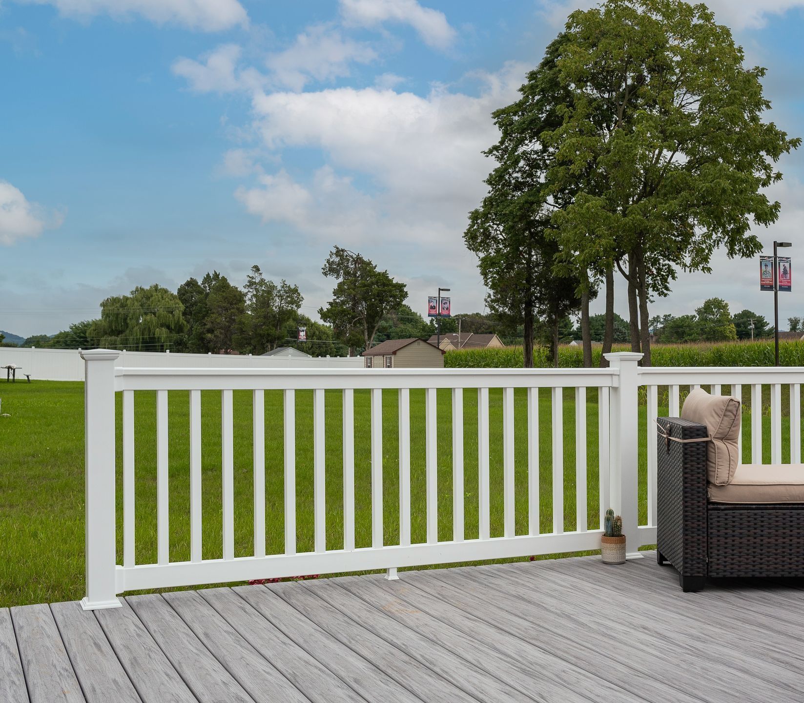 A deck with a white railing and a chair on it