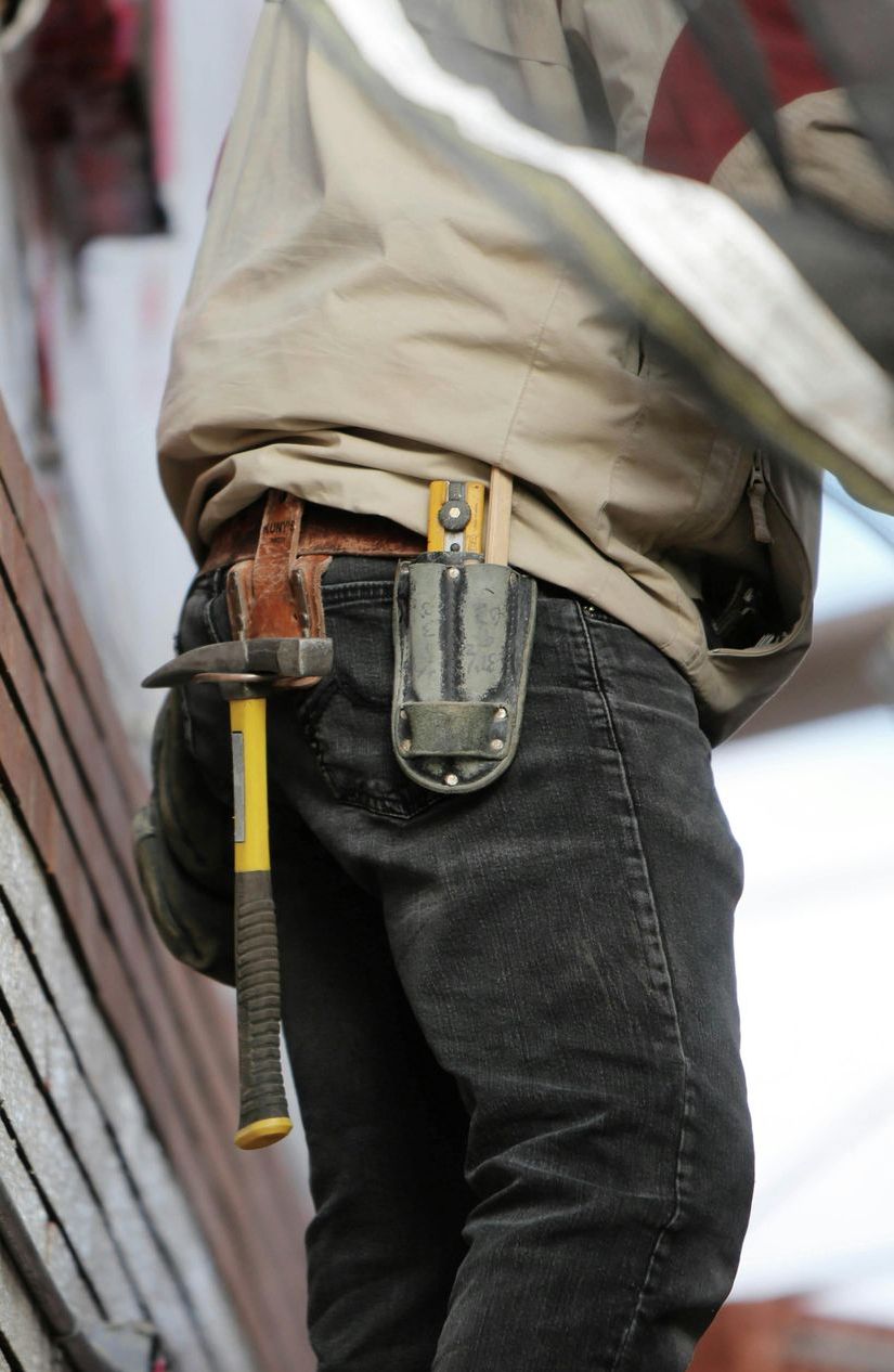 A man wearing a tool belt with a hammer in his pocket