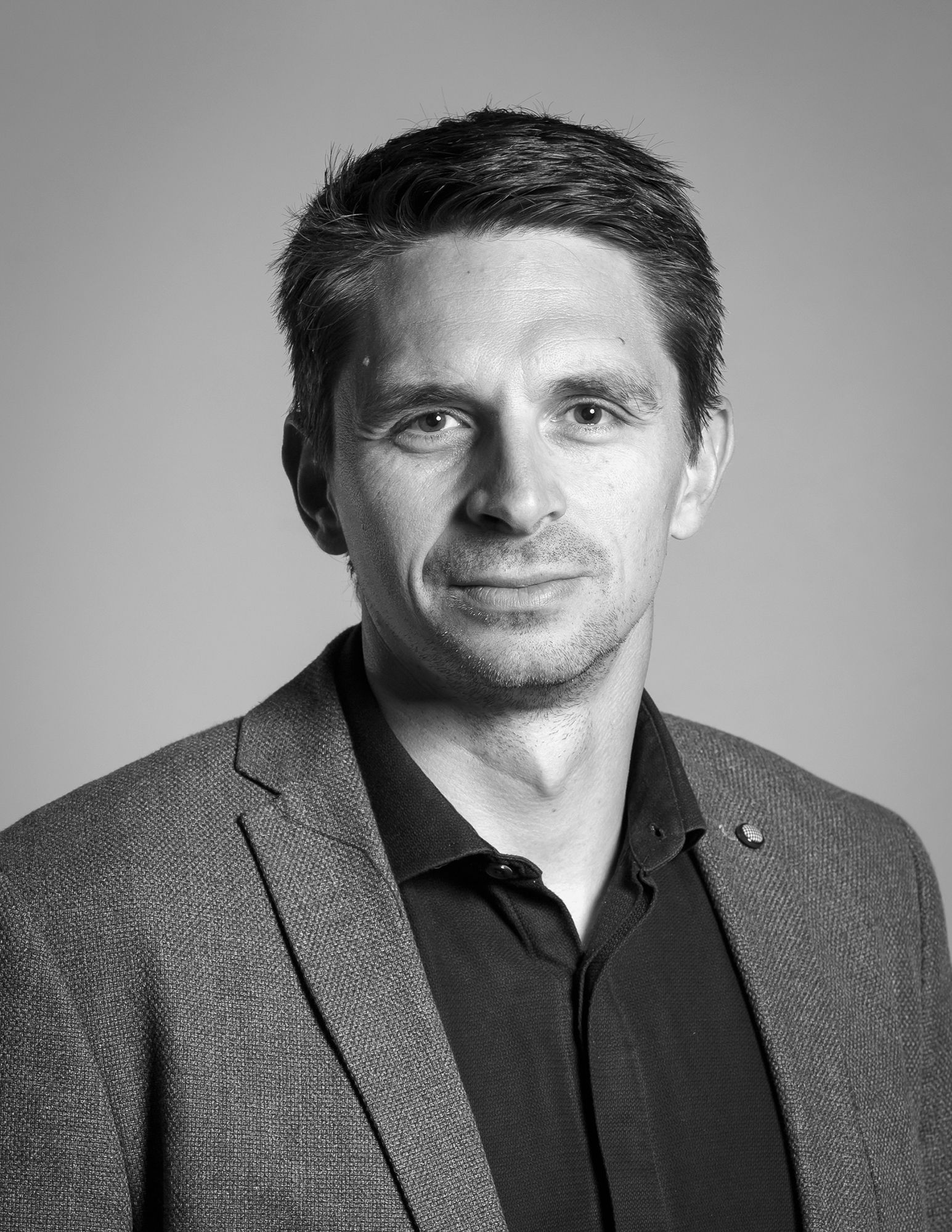 Une photo en noir et blanc d'un homme en costume et chemise.