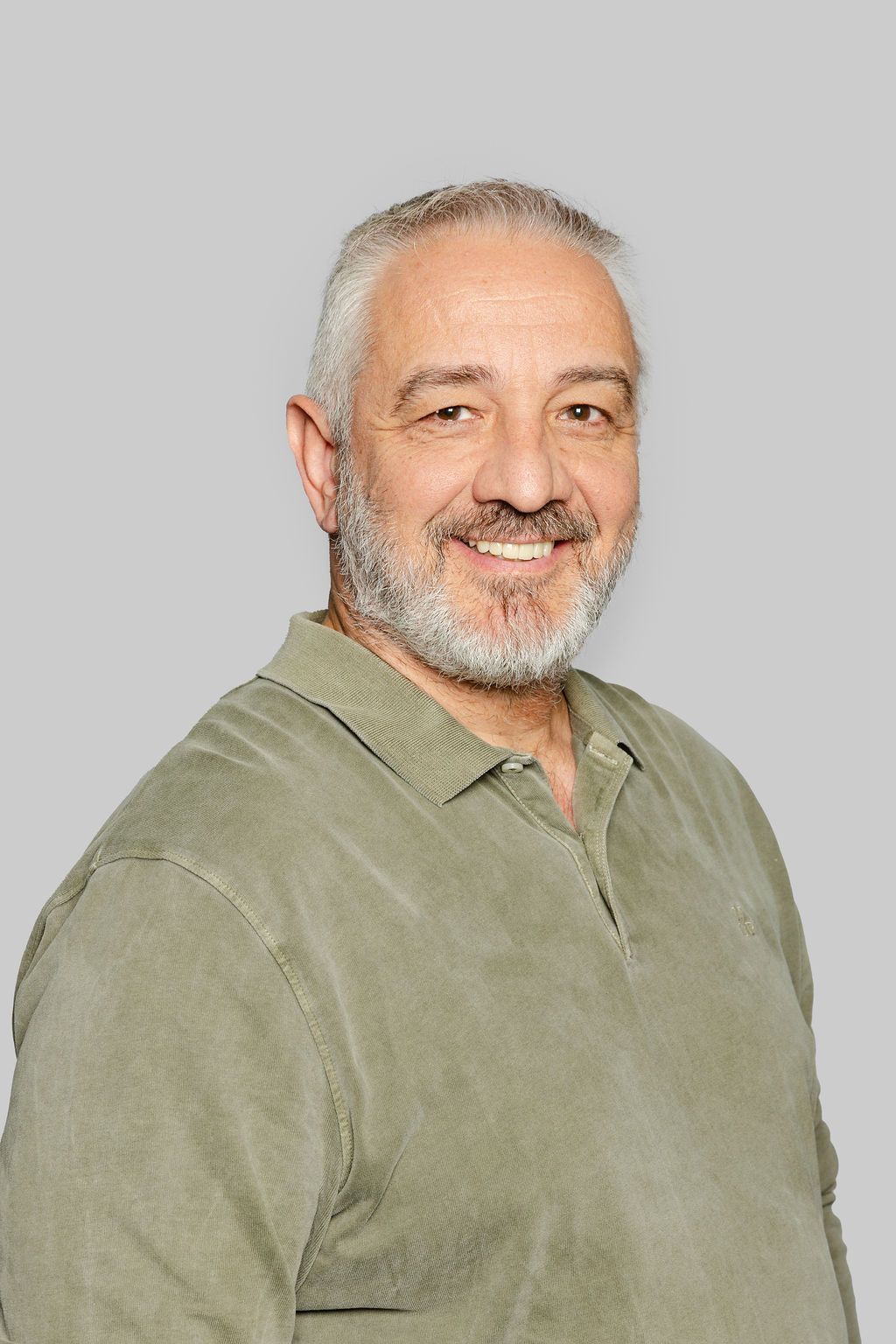 Un homme avec une barbe sourit sur une photo en noir et blanc.