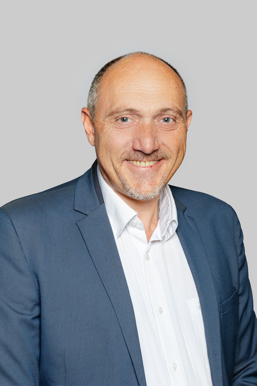 Un homme en costume et chemise blanche sourit sur une photo en noir et blanc.