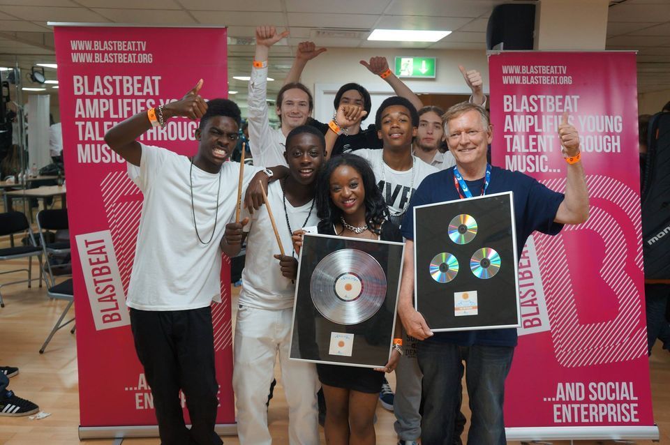 A group of people holding plaques in front of a blastbeat banner