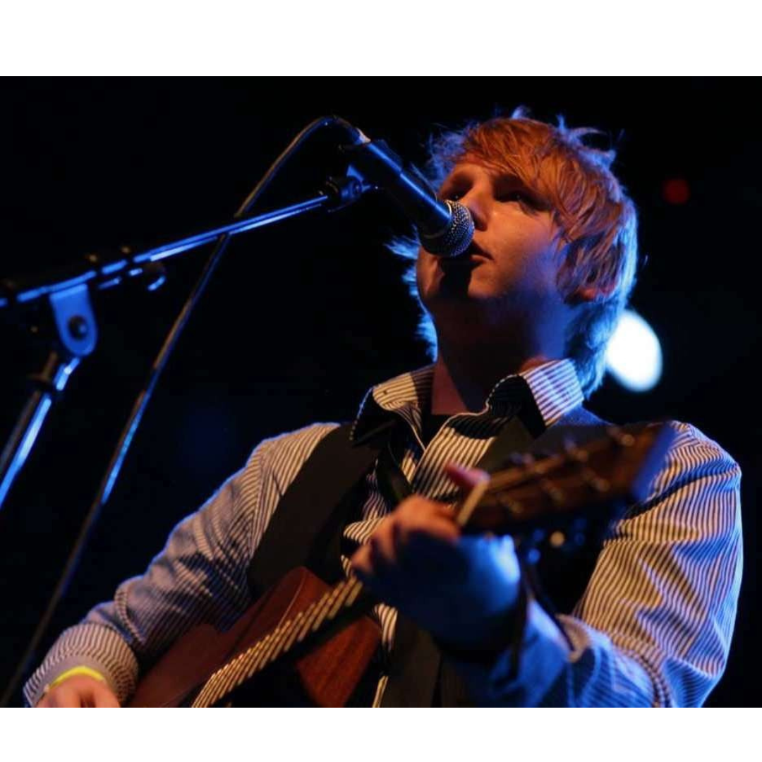 A man singing into a microphone while holding a guitar