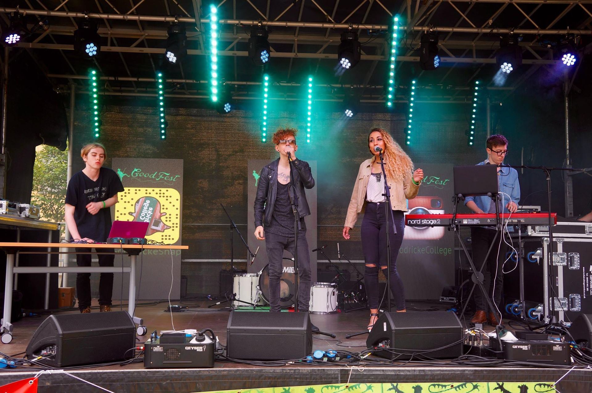 A group of people are standing on a stage singing into microphones.