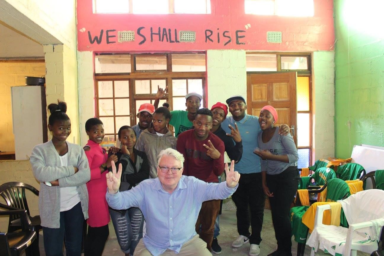 A group of people standing in front of a sign that says we shall rise