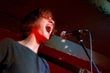 A man is singing into a microphone with his mouth open.
