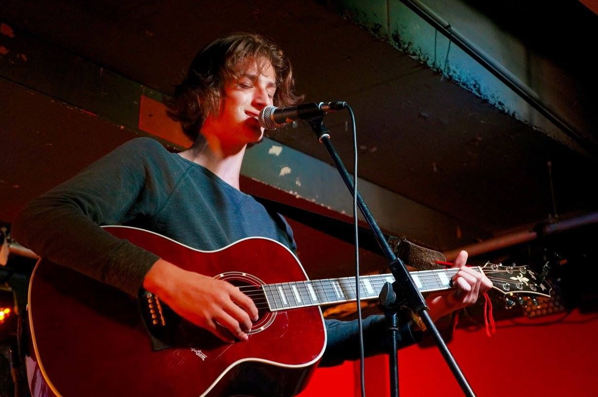 A man is singing into a microphone while playing a guitar.