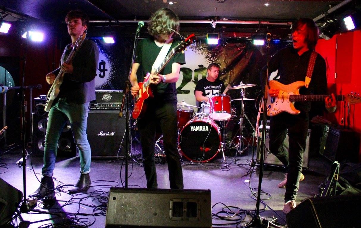 A group of people are playing guitars and drums on a stage.