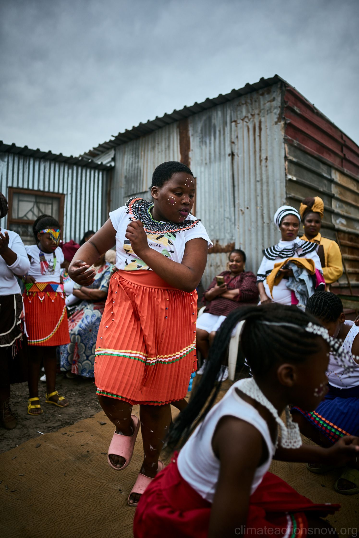 A group of people are dancing in front of a building.