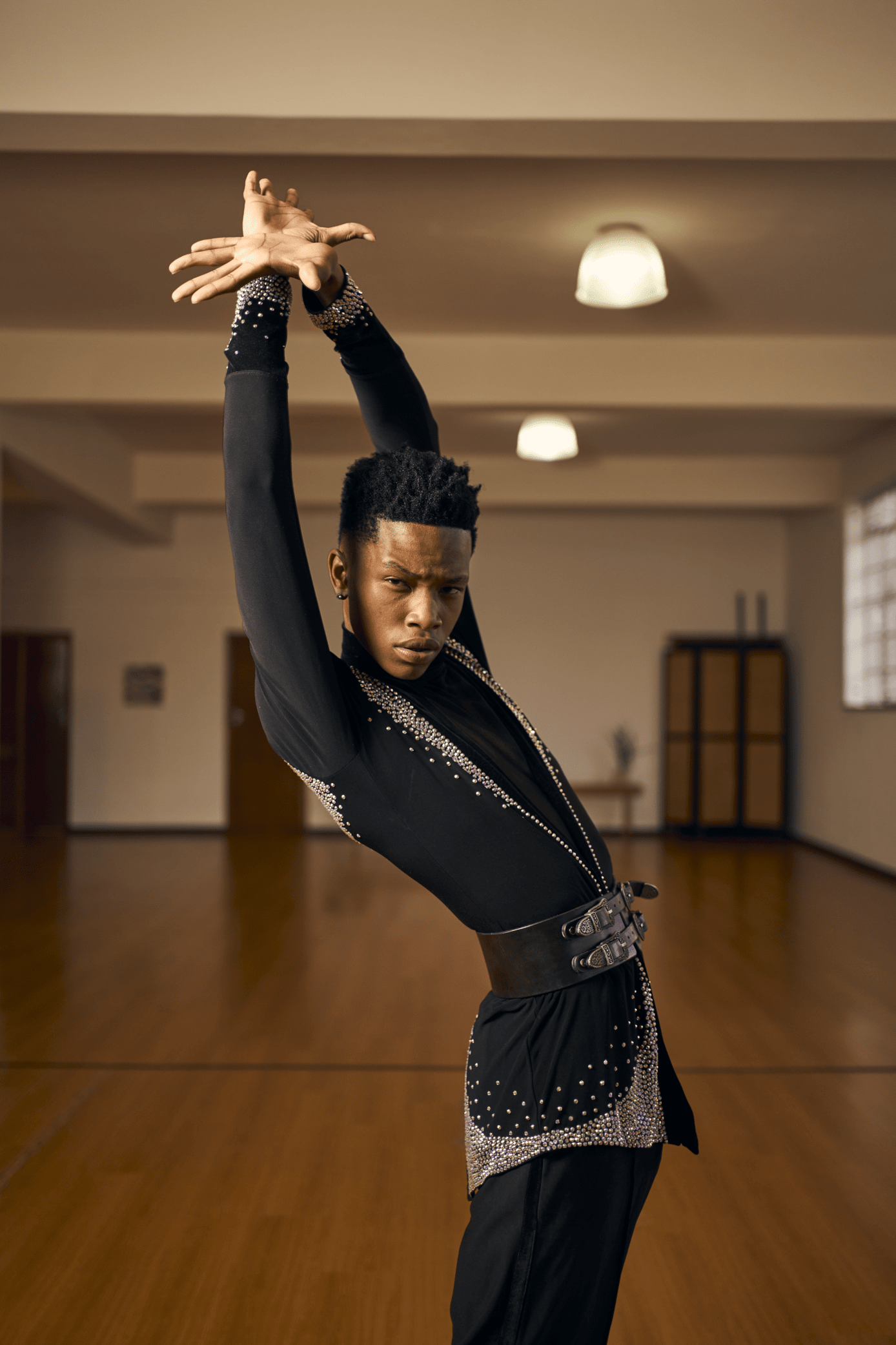 A man in a black suit is dancing in a dance studio.