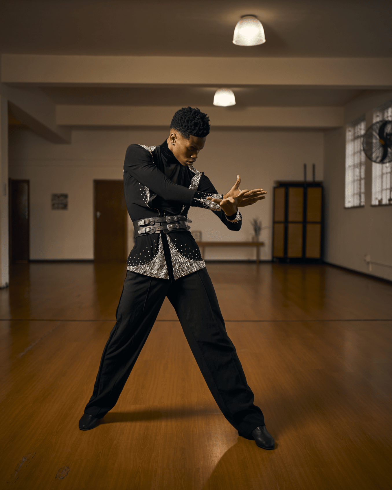 A man in a black suit is dancing in a dance studio.