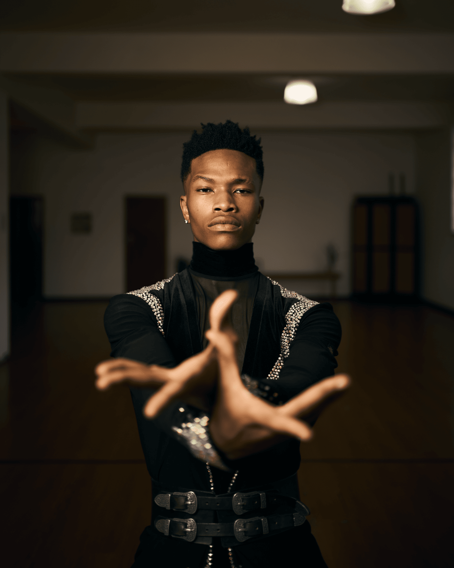 A young man is standing in a dark room with his hands outstretched.