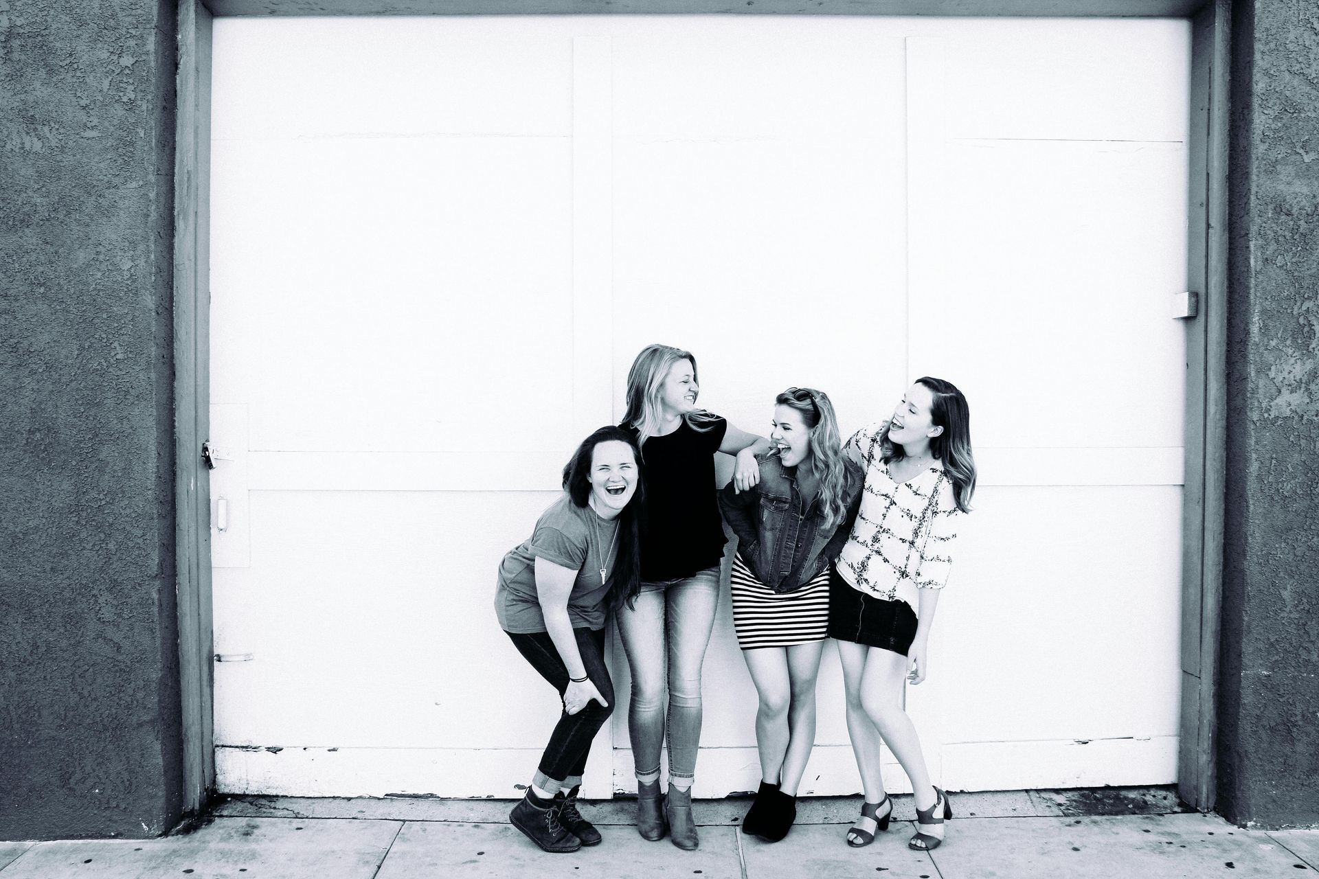 A group of young women are posing for a picture in front of a garage door.