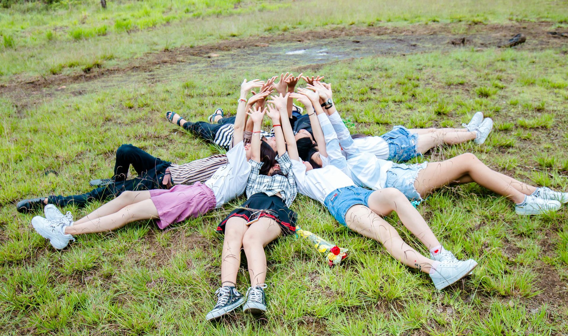 A group of young women are laying on the grass in a circle.