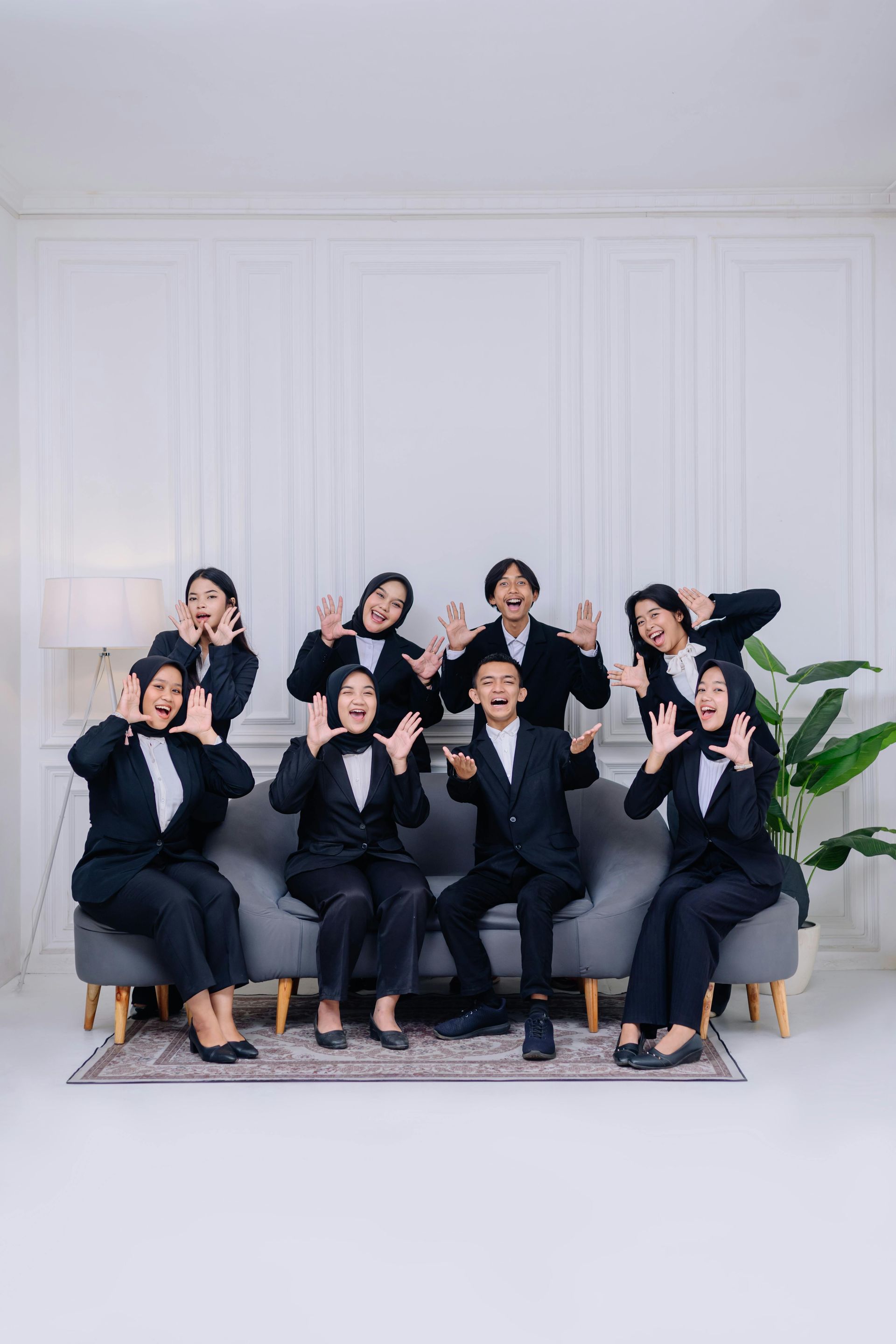 A group of people in tuxedos are posing for a picture while sitting on a couch.