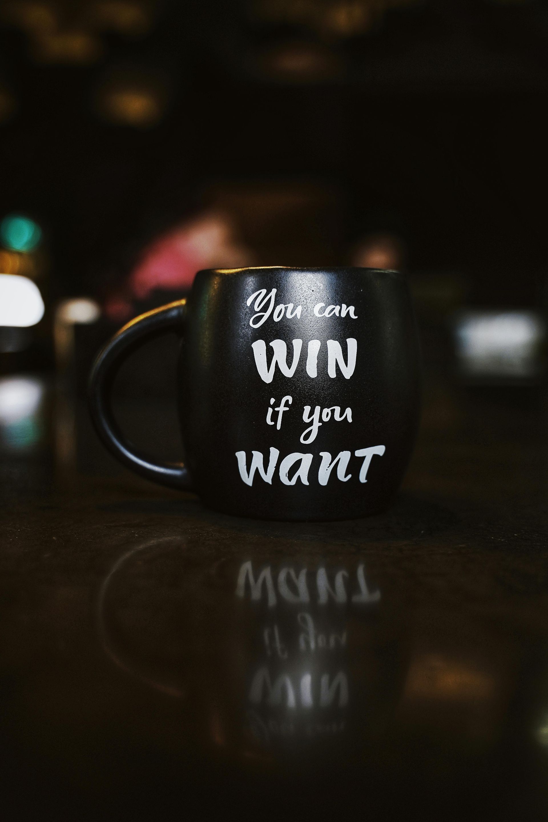A black coffee mug that says `` you can win if you want '' is sitting on a table.