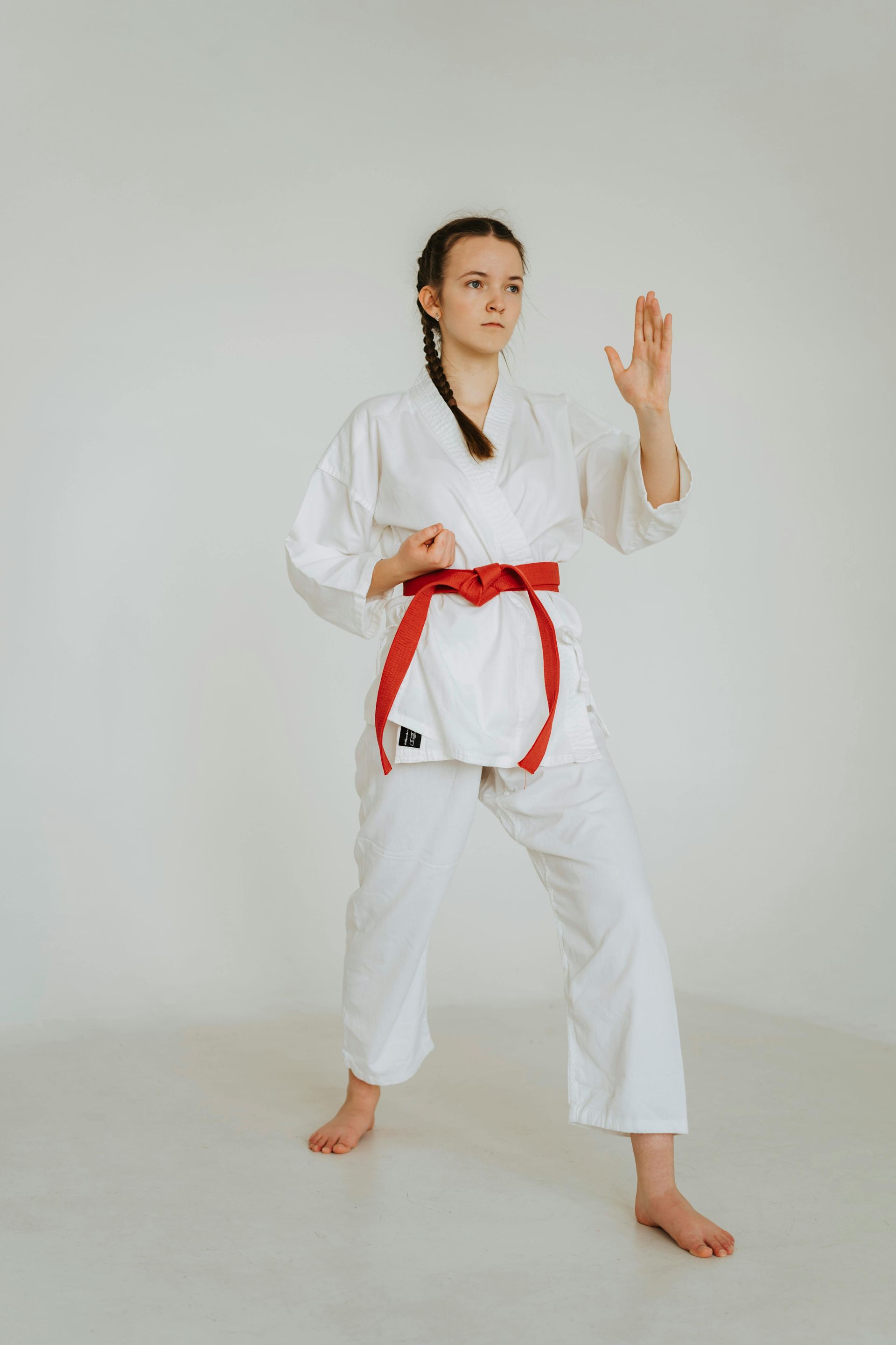 A woman in a white karate uniform with a red belt.