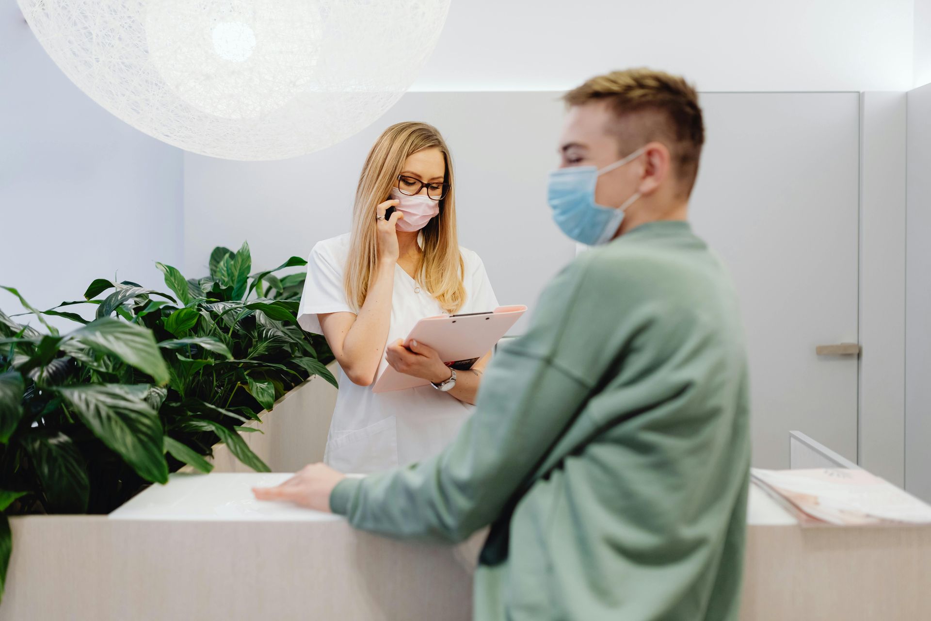 A woman wearing a mask is talking on a cell phone to a man wearing a mask.