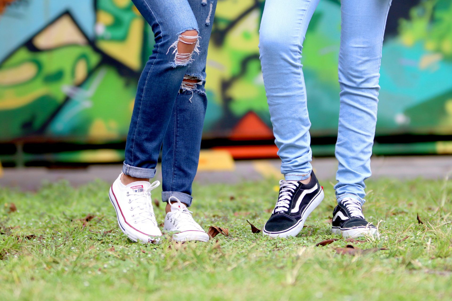A couple of people standing next to each other in front of a graffiti wall.