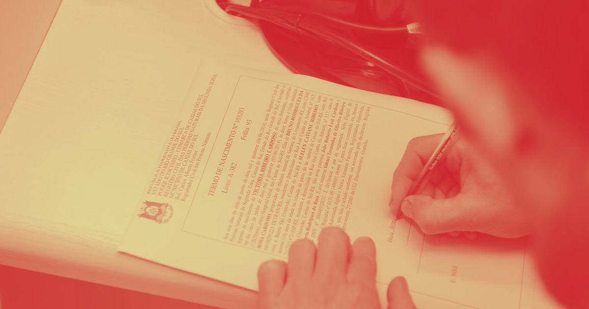 Pessoa escrevendo em um documento com uma caneta de cor vermelha.