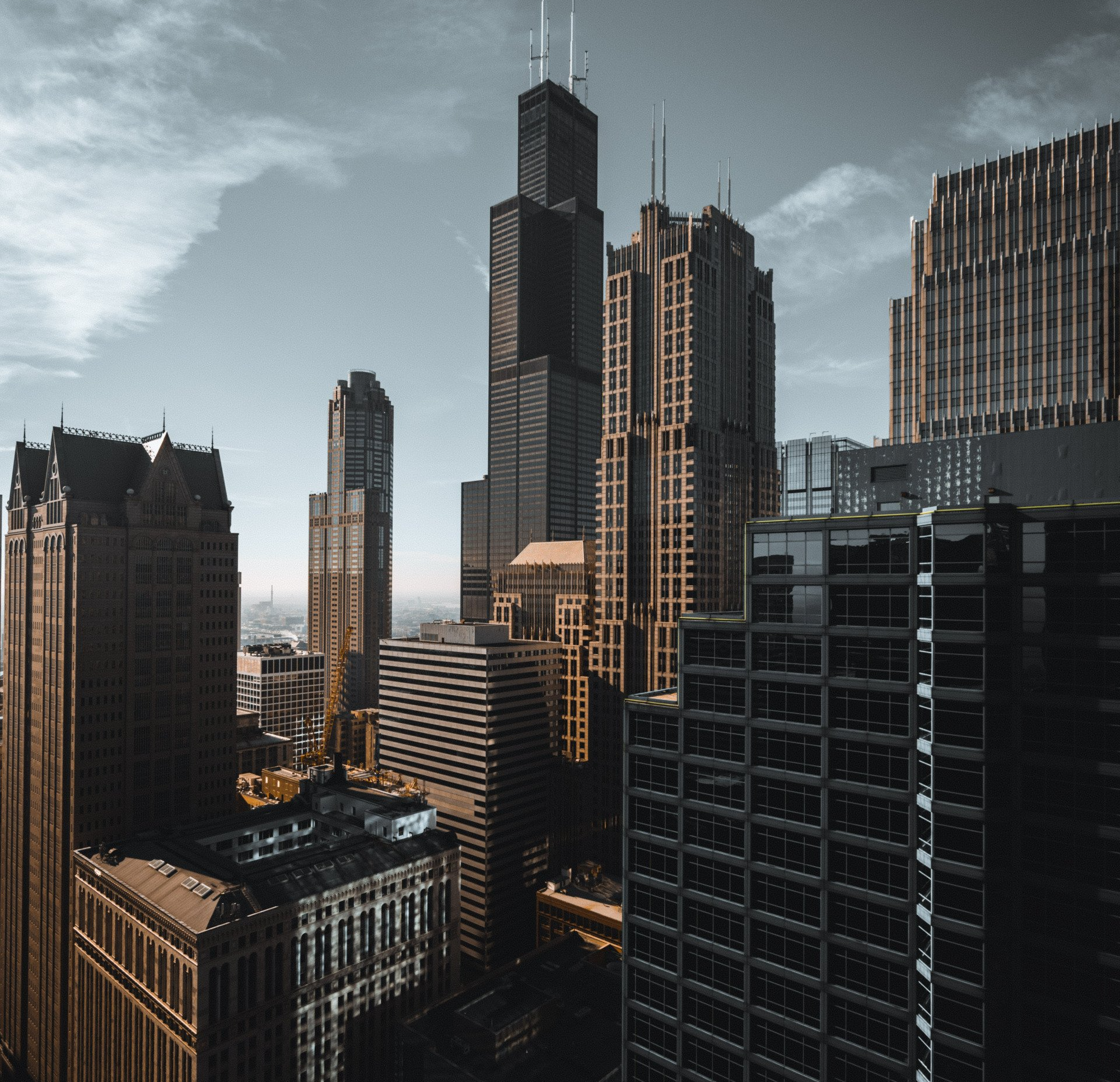 Horizonte de Chicago: arranha-céus imponentes sob um céu parcialmente nublado, com edifícios em tons de marrom e cinza.