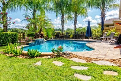 A well landscaped backyard pool with pool patio in Oxnard, Ca.  Nicely trimmed palm trees, green grass and stamped concrete patio make this a very beautiful yard.