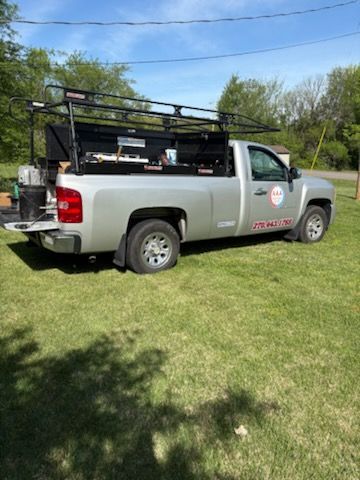 A silver truck is parked in a grassy field.