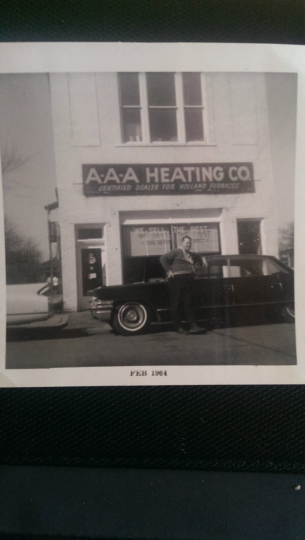 A black and white photo of a car parked in front of a building.