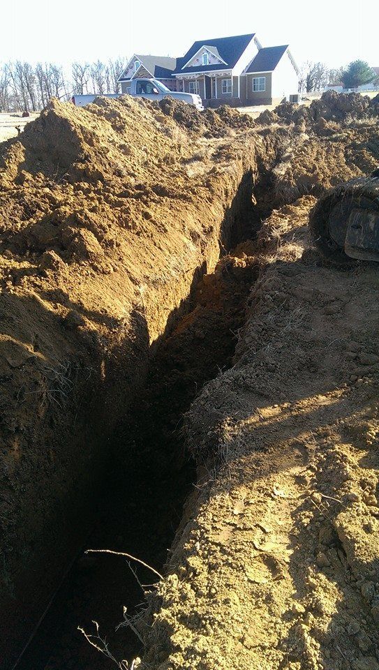 A large pile of dirt is being excavated in front of a house.