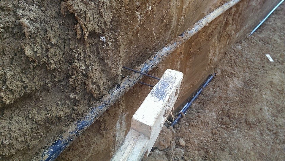 A pipe is laying in the dirt next to a brick.