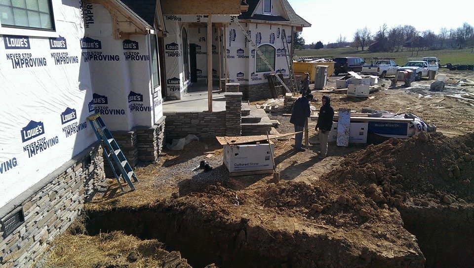 A large hole in the ground in front of a house that is being built