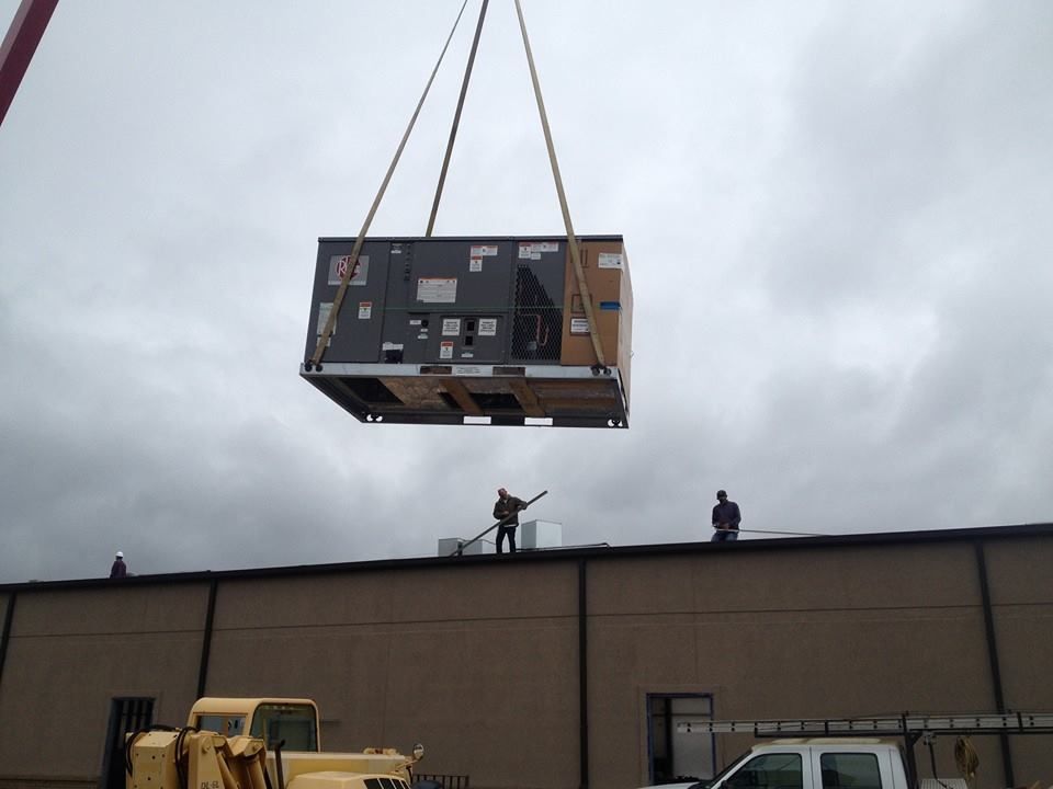 A large box is being lifted by a crane on top of a building