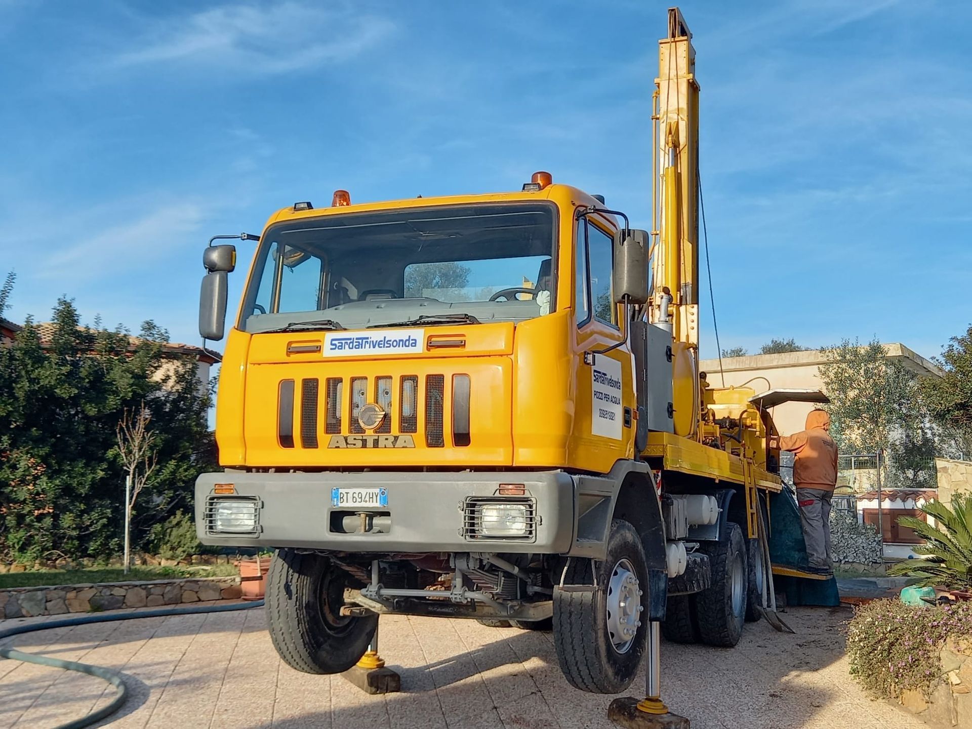 Camion di perforazione giallo su terreno asfaltato con stabilizzatori sollevati e cielo azzurro Sarda Trivelsonda Group Olbia  Loiri Porto San Paolo - Loiri (SS)